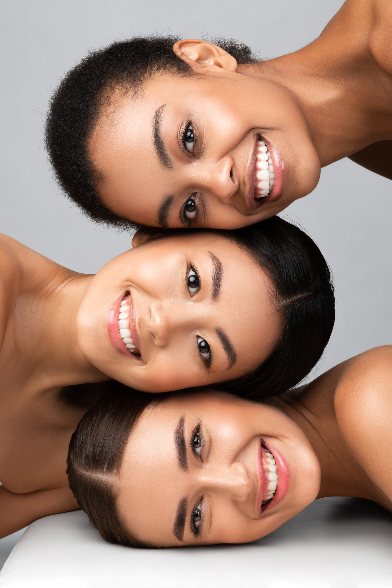 3 multi-racial women faces layered on top of each other for facials