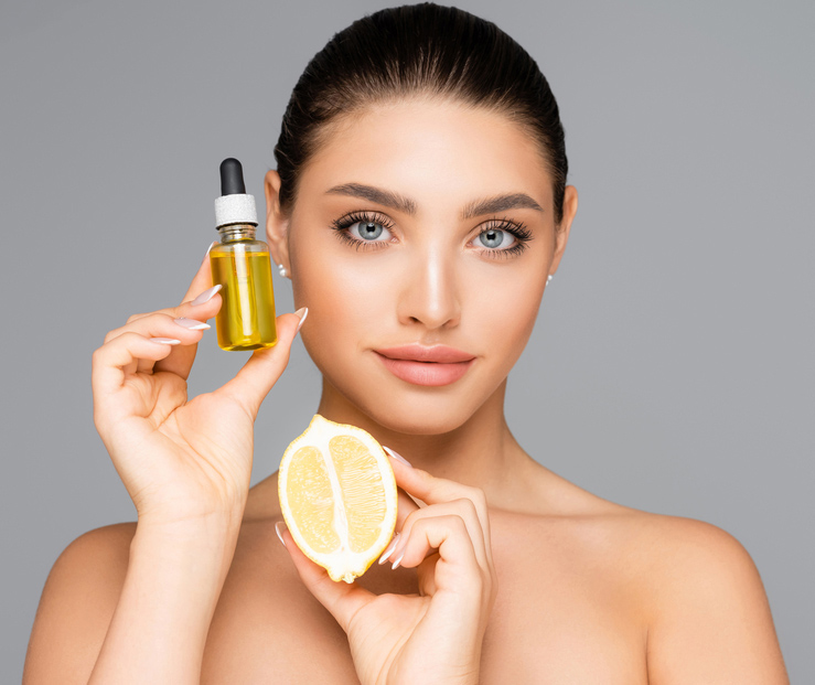 woman holding a lemon and bottle of essential oil used for chemical peels
