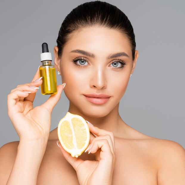 woman holding a lemon and bottle of essential oil used for chemical peels